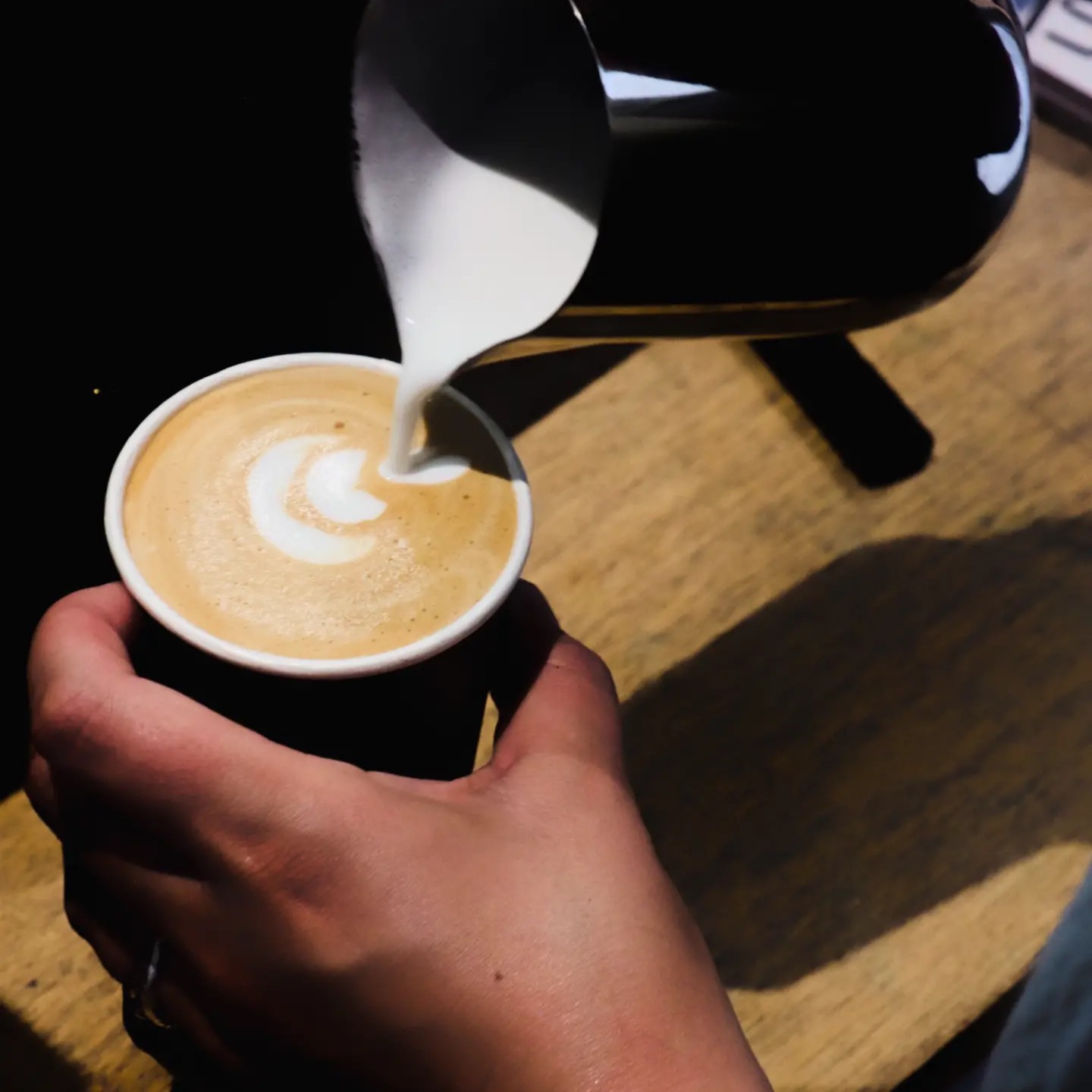 Pouring latte art into a cup at Hazeldines